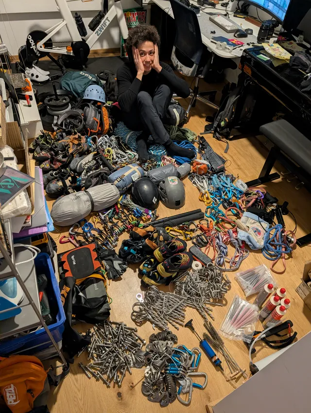 Benjamin sitting in a room completely covered in climbing gear